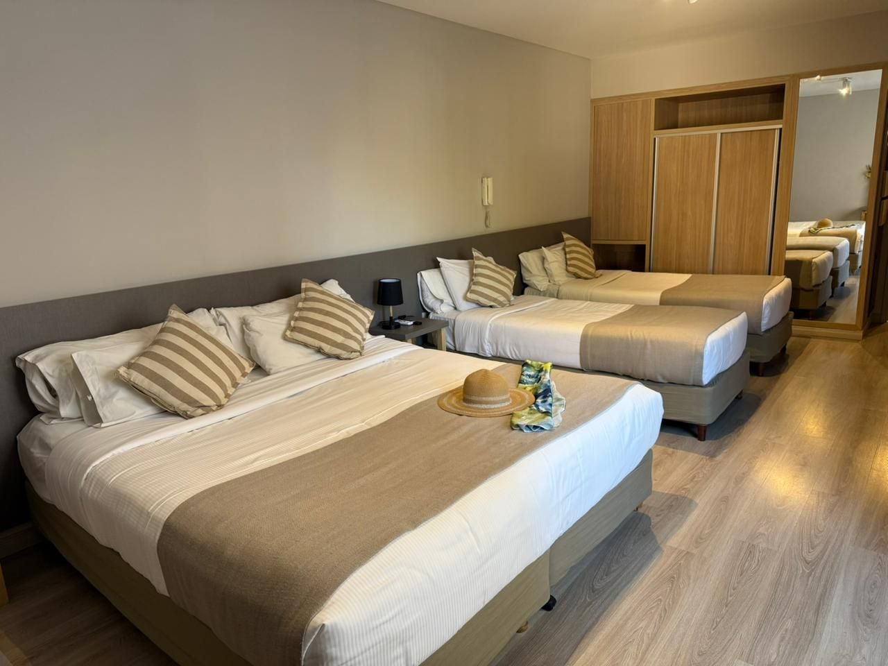 A hotel room with two beds, a wardrobe, and a bathroom visible through an open door.