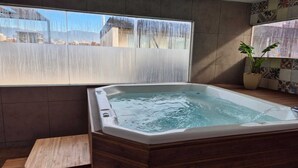Un baño moderno con una bañera de madera, un ventanal grande y una planta en maceta.