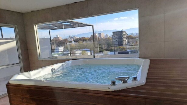 Un jacuzzi en una habitación con ventanas amplias con vistas a la ciudad.