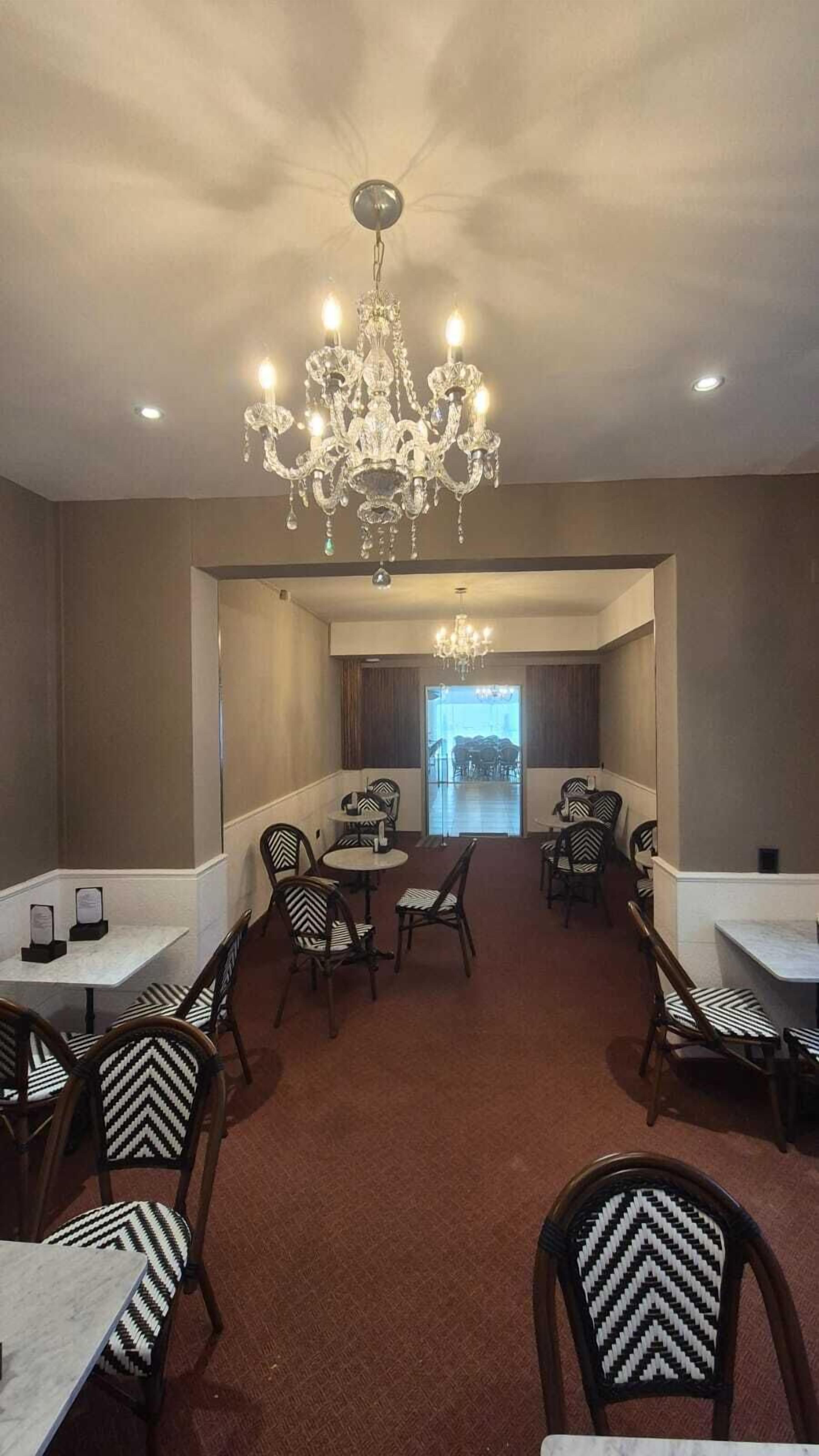 Ein Hotelzimmer mit einer Chandelüster, mehreren Tischen und Stühlen, die zum Essen bereitstehen.