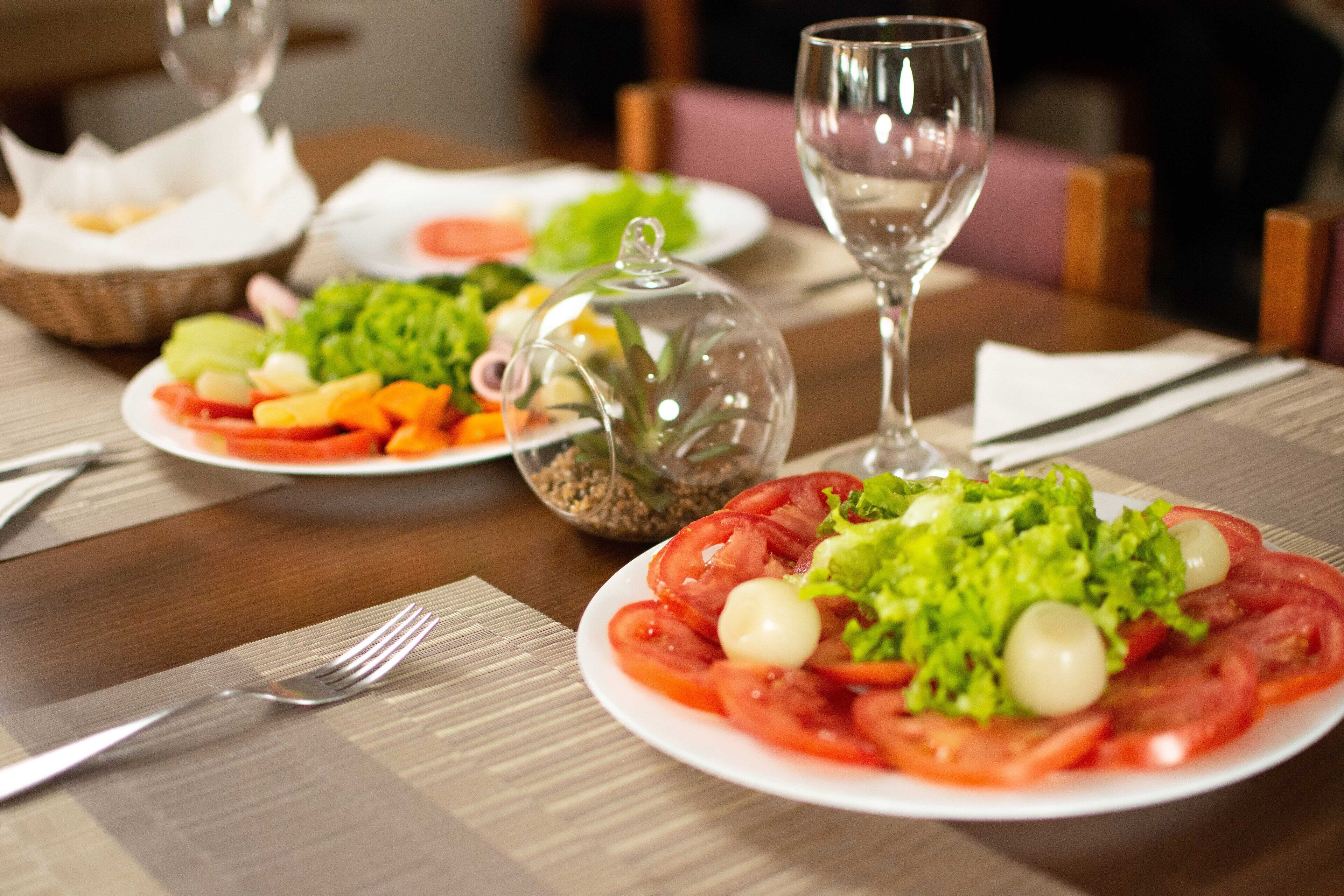 Una mesa de comedor con platos de comida, un vaso de agua y un tenedor.