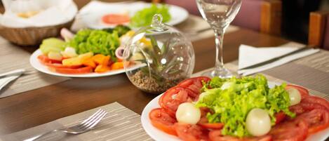 Una mesa de comedor con platos de comida, un vaso de agua y un tenedor.