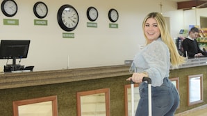 A reception area with clocks displaying times from various cities, a computer monitor, and framed mirrors on the wall.