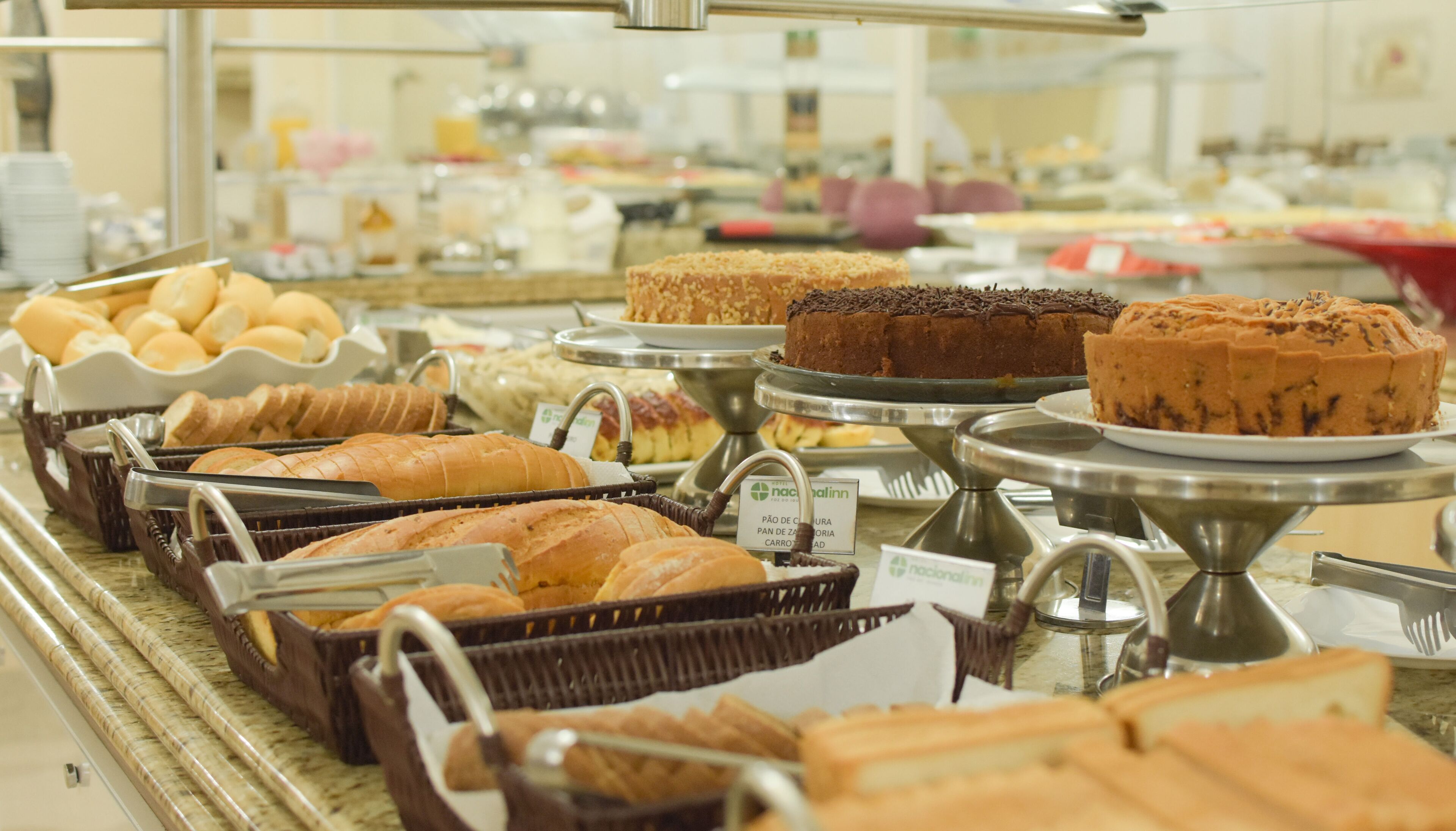 A buffet with various breads, pastries, and cakes.
