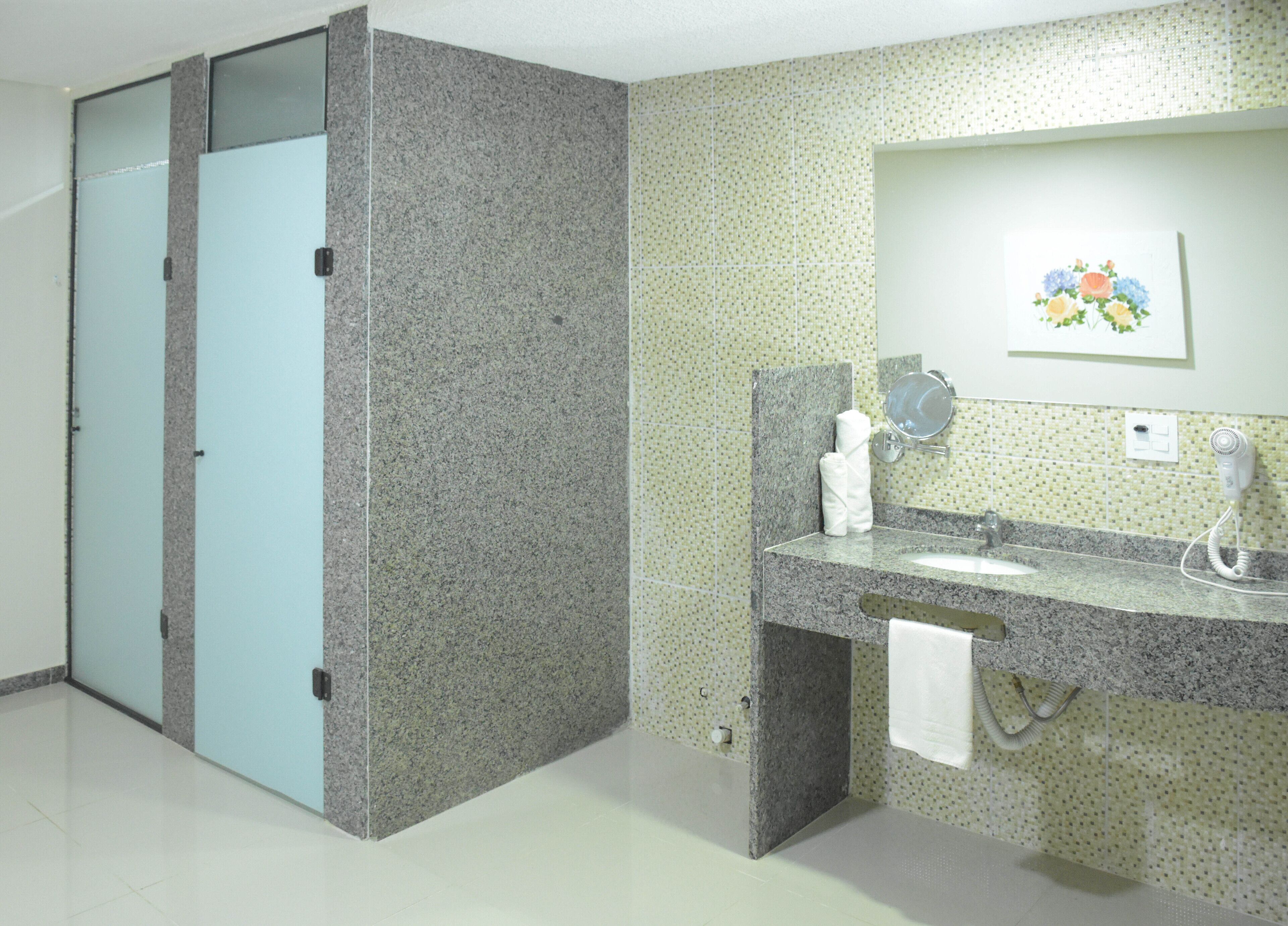 A bathroom with a granite countertop, a sink, a mirror, a towel rack, and a toilet.