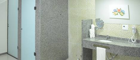 A bathroom with a granite countertop, a sink, a mirror, a towel rack, and a toilet.