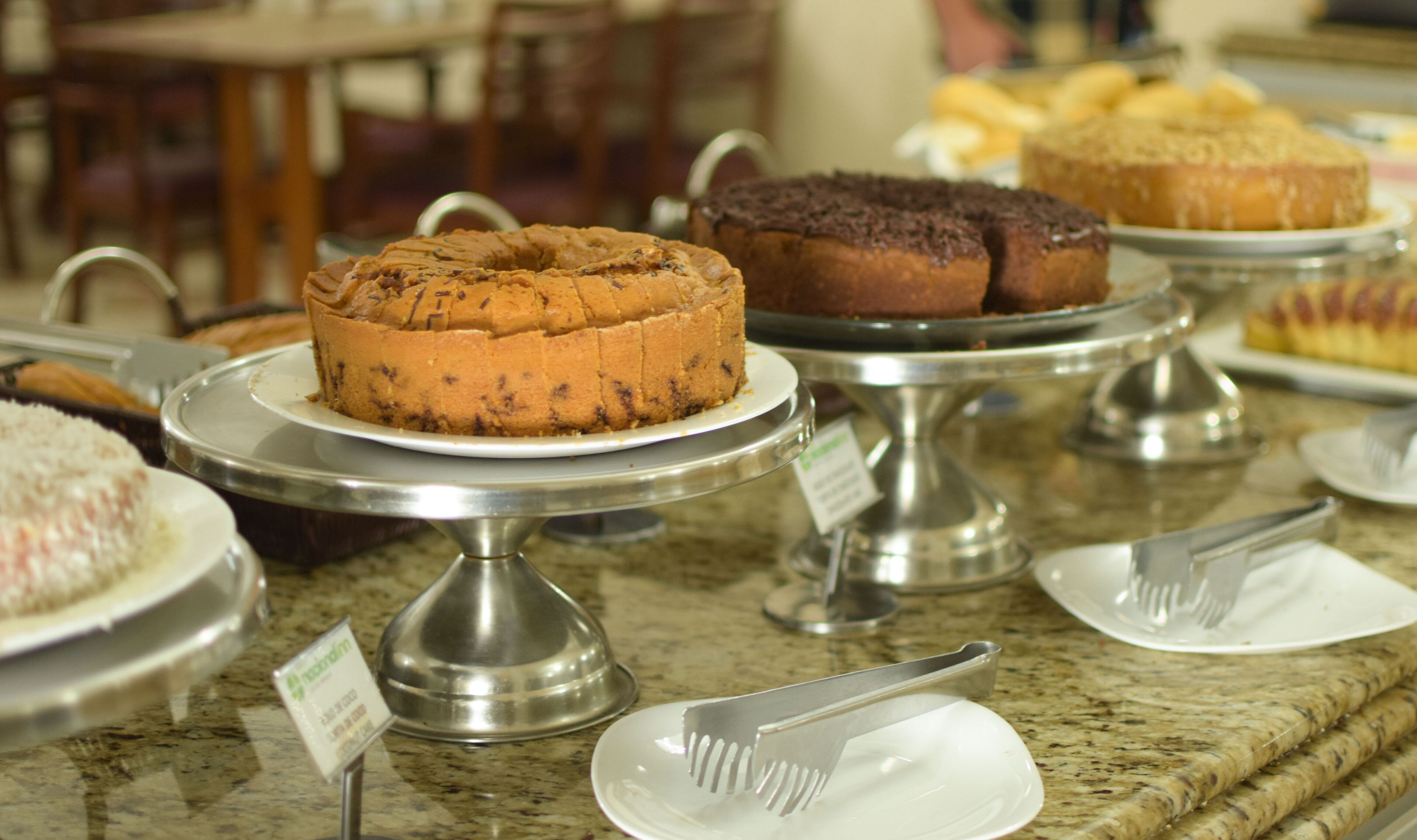 A buffet with various cakes and pastries on display.