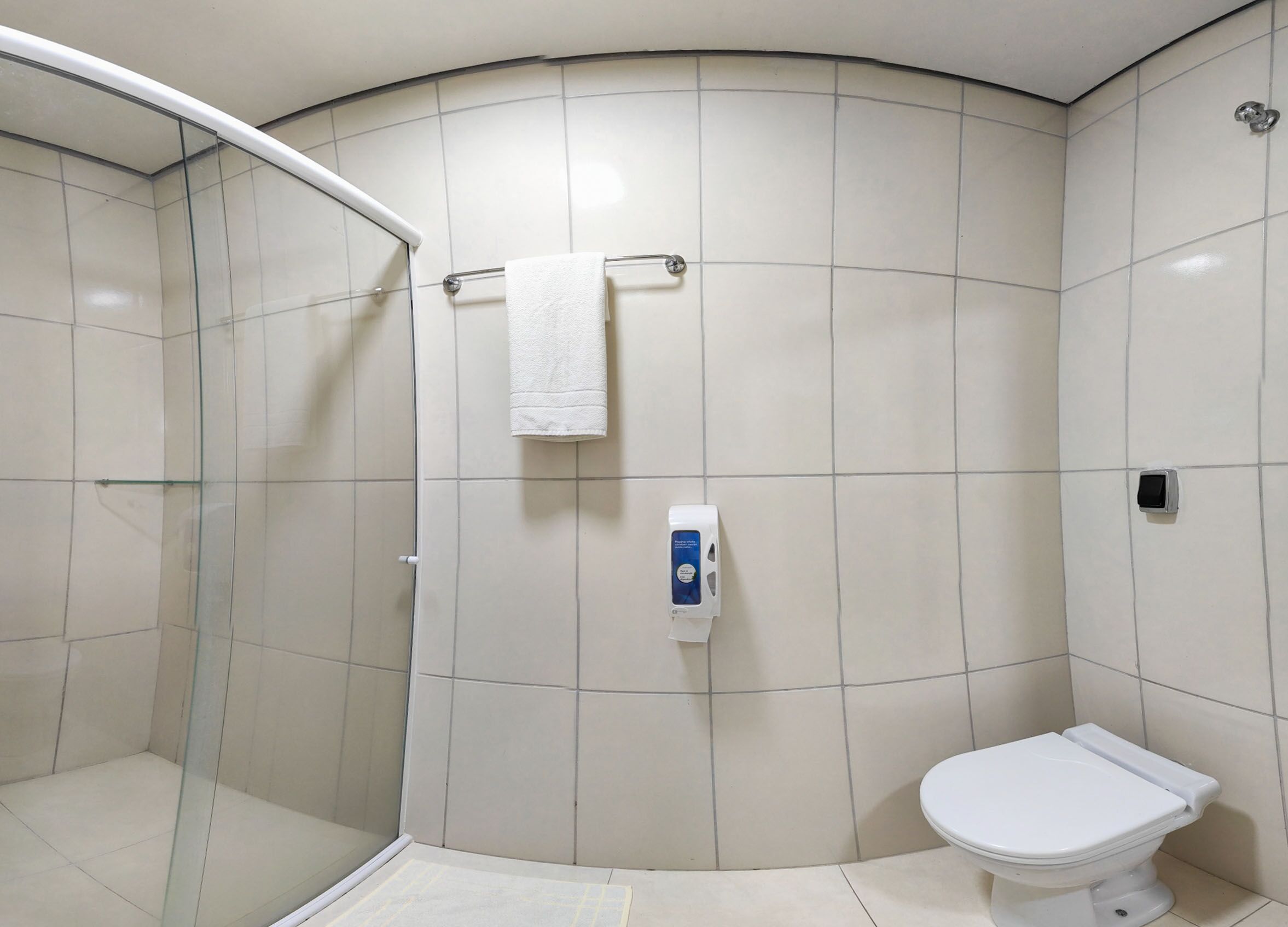 Un baño con cabina de ducha de vidrio, inodoro y secador de manos.