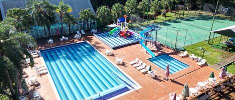 Una piscina techada, una piscina al aire libre, sombrillas