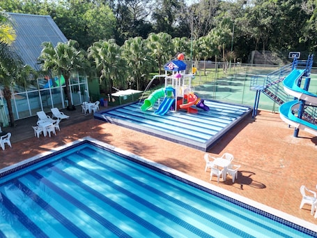 Una piscina techada, una piscina al aire libre, sombrillas