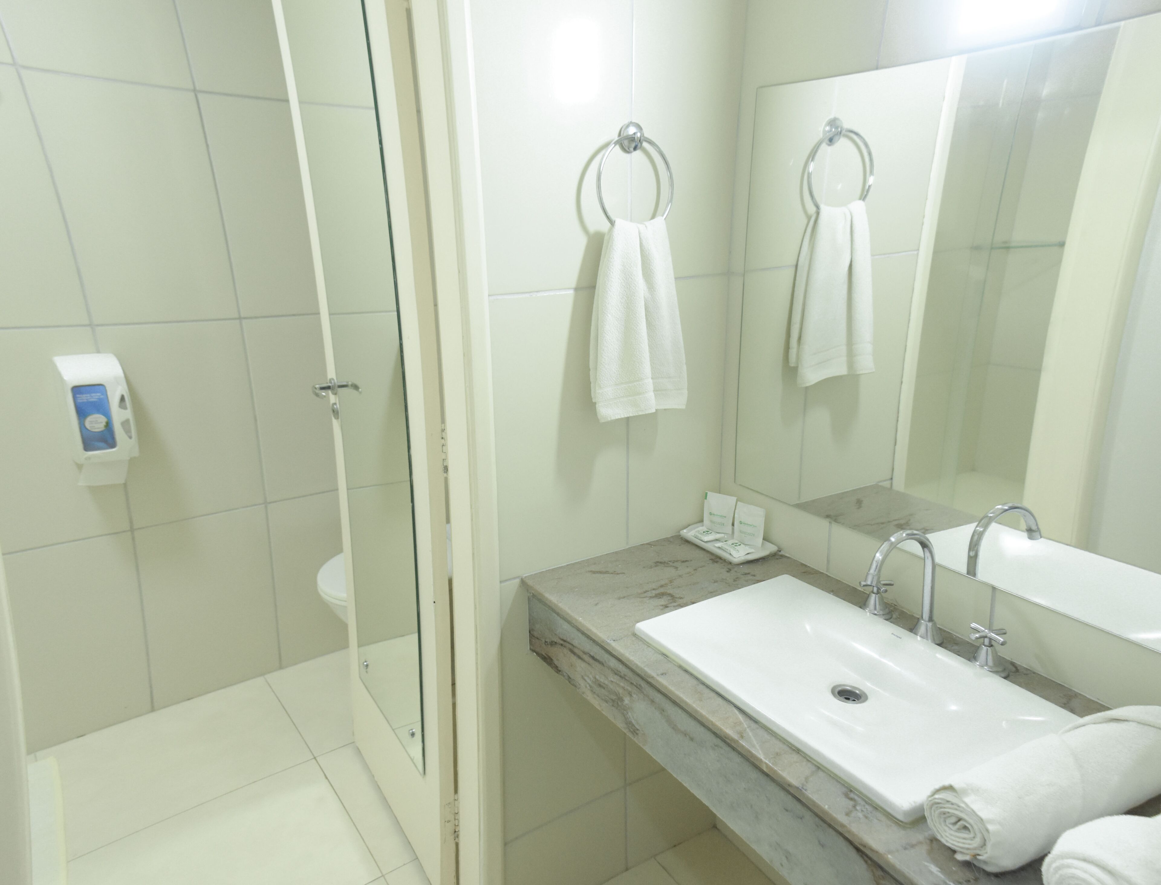 A modern bathroom with a glass shower enclosure, a marble countertop, a sink, and two towel rings.