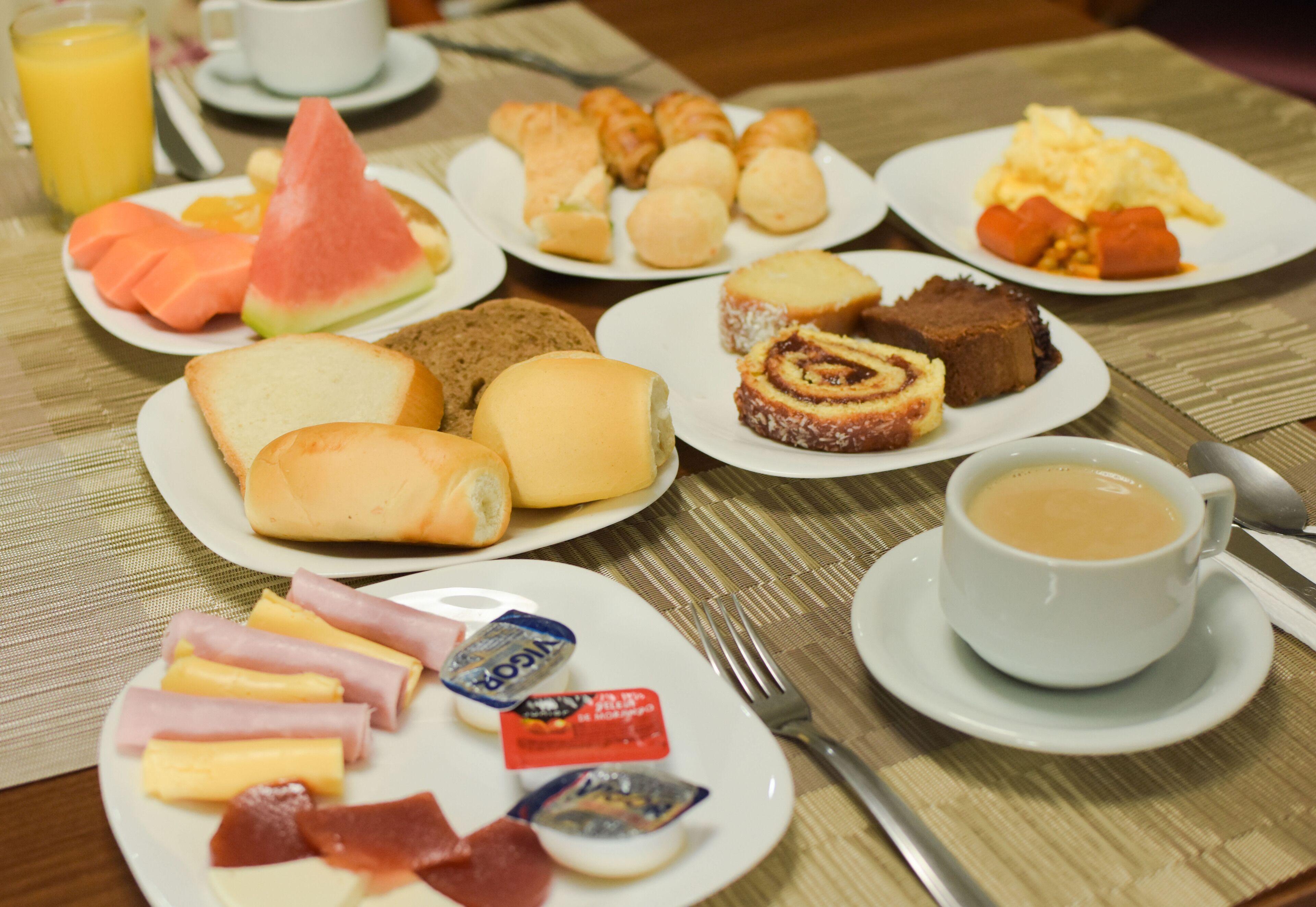 Un bufé de desayuno con diversas opciones de comida, como pan, bollería, frutas y bebidas.