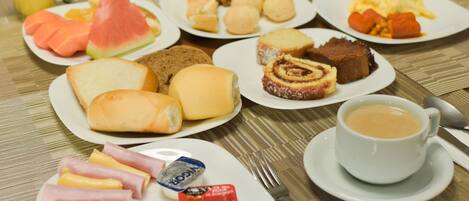Un bufé de desayuno con diversas opciones de comida, como pan, bollería, frutas y bebidas.