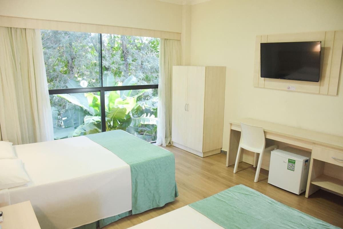 A hotel room with two beds, a desk, a TV, and a wardrobe.