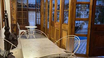 A wooden-paneled room with a table and chairs, a chandelier, and large windows.