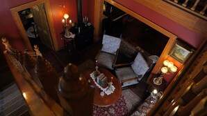 Une pièce chaleureuse avec un escalier en bois, une table ronde décorée de bougies et un canapé confortable.
