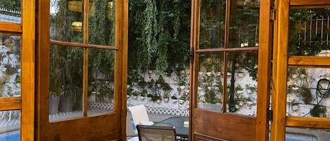 A wooden door with glass panels leading to an outdoor patio area with a table and chairs.
