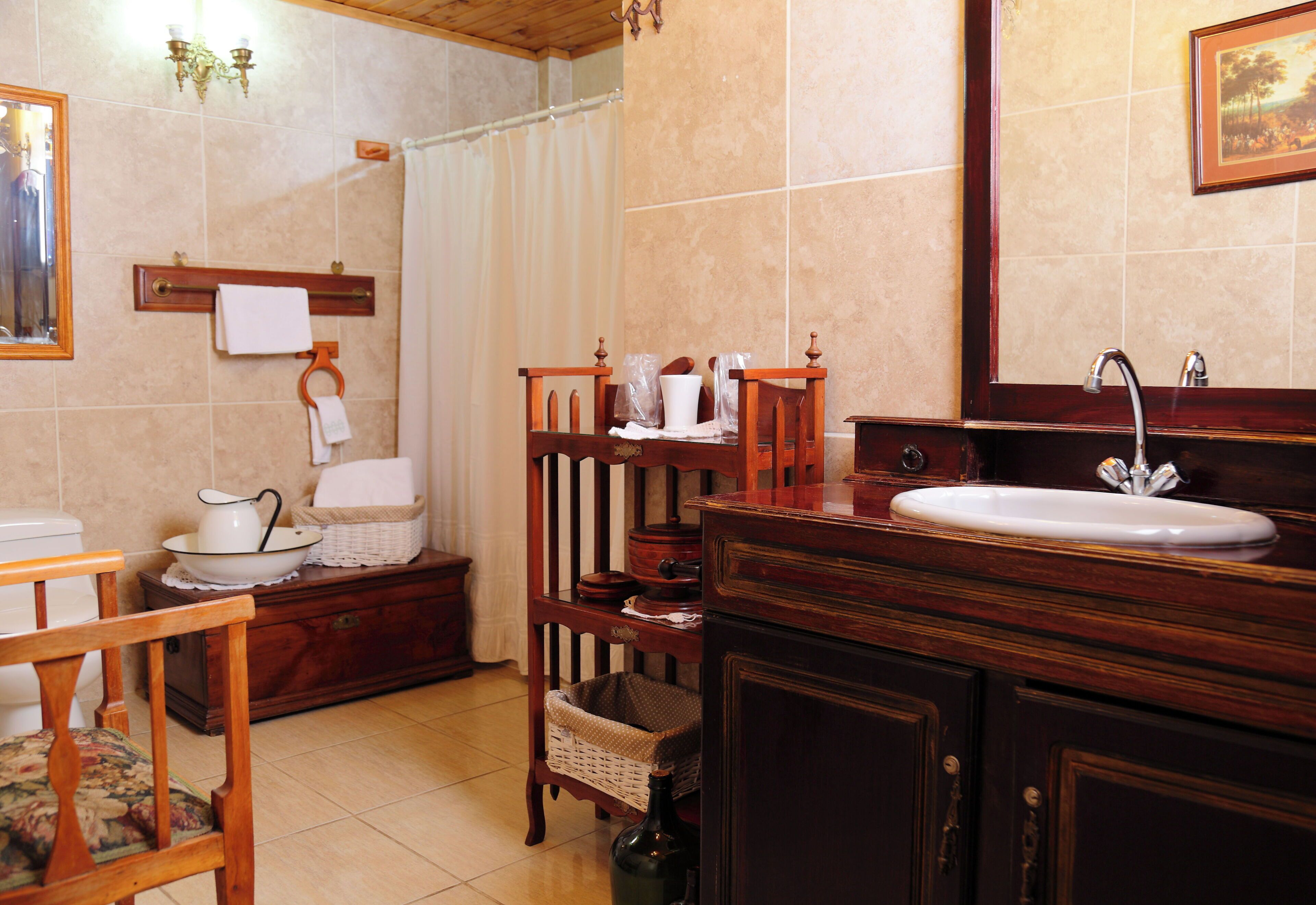 Une salle de bain avec un meuble-lavabo en bois, un évier, un miroir, un porte-serviettes et un panier en osier.