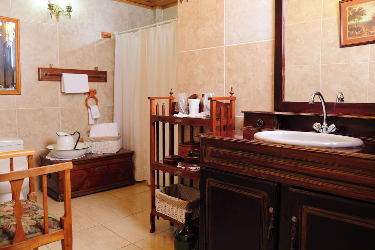 Une salle de bain avec un meuble-lavabo en bois, un évier, un miroir, un porte-serviettes et un panier en osier.