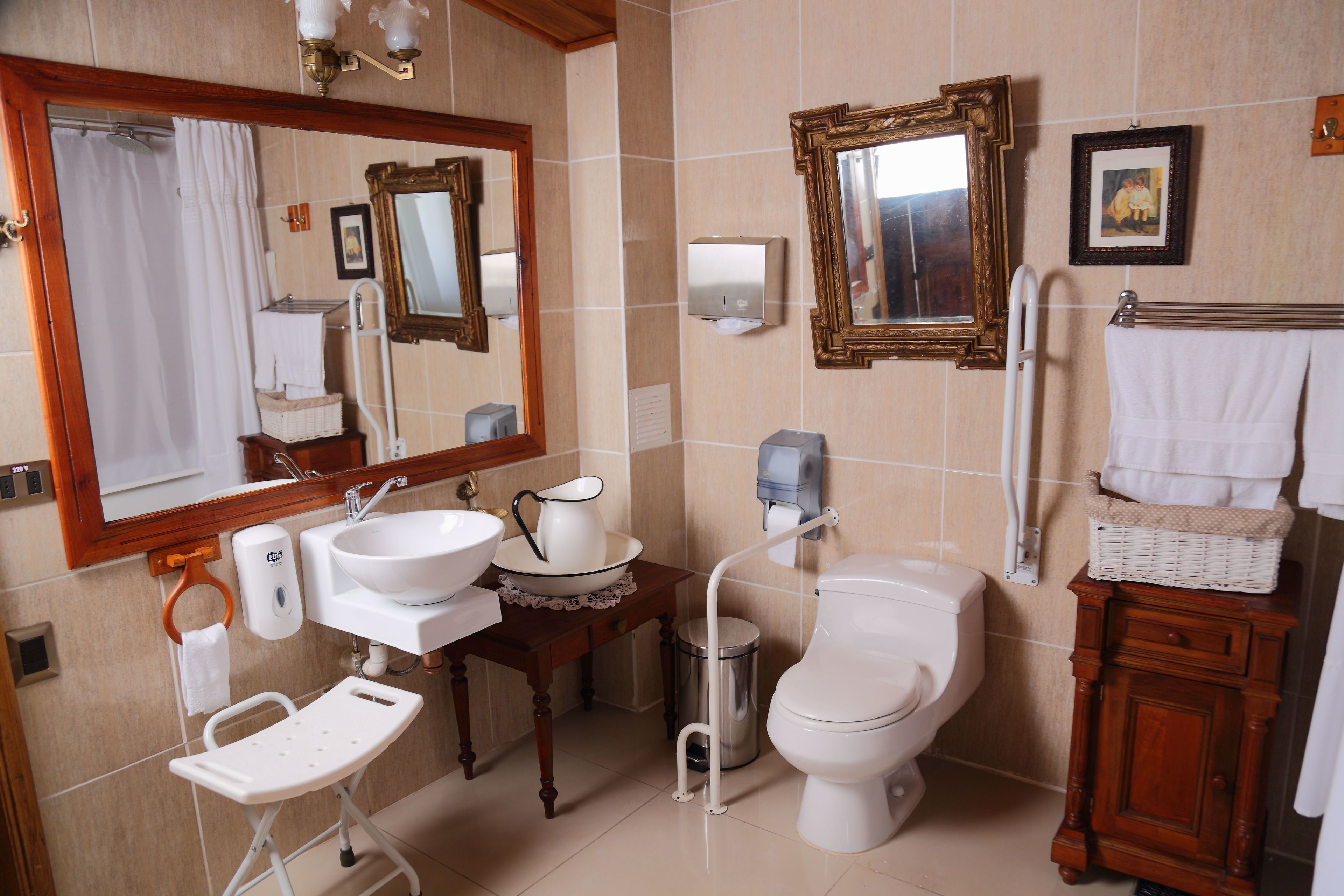 A bathroom with a sink, mirror, toilet, and a small table with a basket.