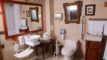 A bathroom with a sink, mirror, toilet, and a small table with a basket.