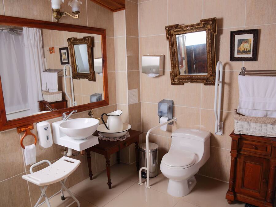 A bathroom with a sink, mirror, toilet, and a small table with a basket.