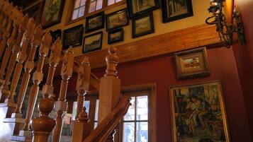 Una escalera con balaustres de madera, un cuadro con la imagen de dos personas y varias fotografías enmarcadas en la pared.