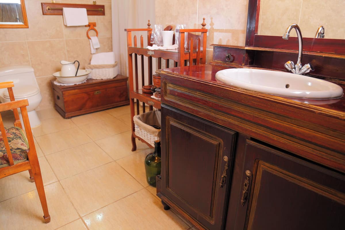 Un baño con tocador de madera, lavamanos y retrete.
