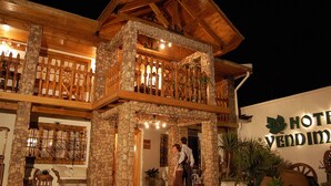 Un hôtel à la façade en pierre, doté de balcons en bois et d’une enseigne sur laquelle on peut lire « HÔTEL VENDIMIO ».
