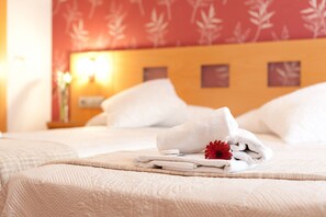 A neatly made bed with white linens and a red flower decoration. - Hostal Abami II (Madrid)