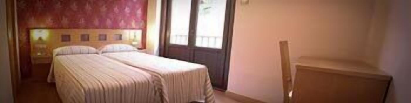 A double bed in a room with a wooden headboard and a window with a view of the outside.