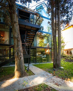 A modern building with a glass facade, a wooden staircase, and a stone pathway. - Villa Sofia Apart Hotel & Spa (San Carlos de Bariloche)