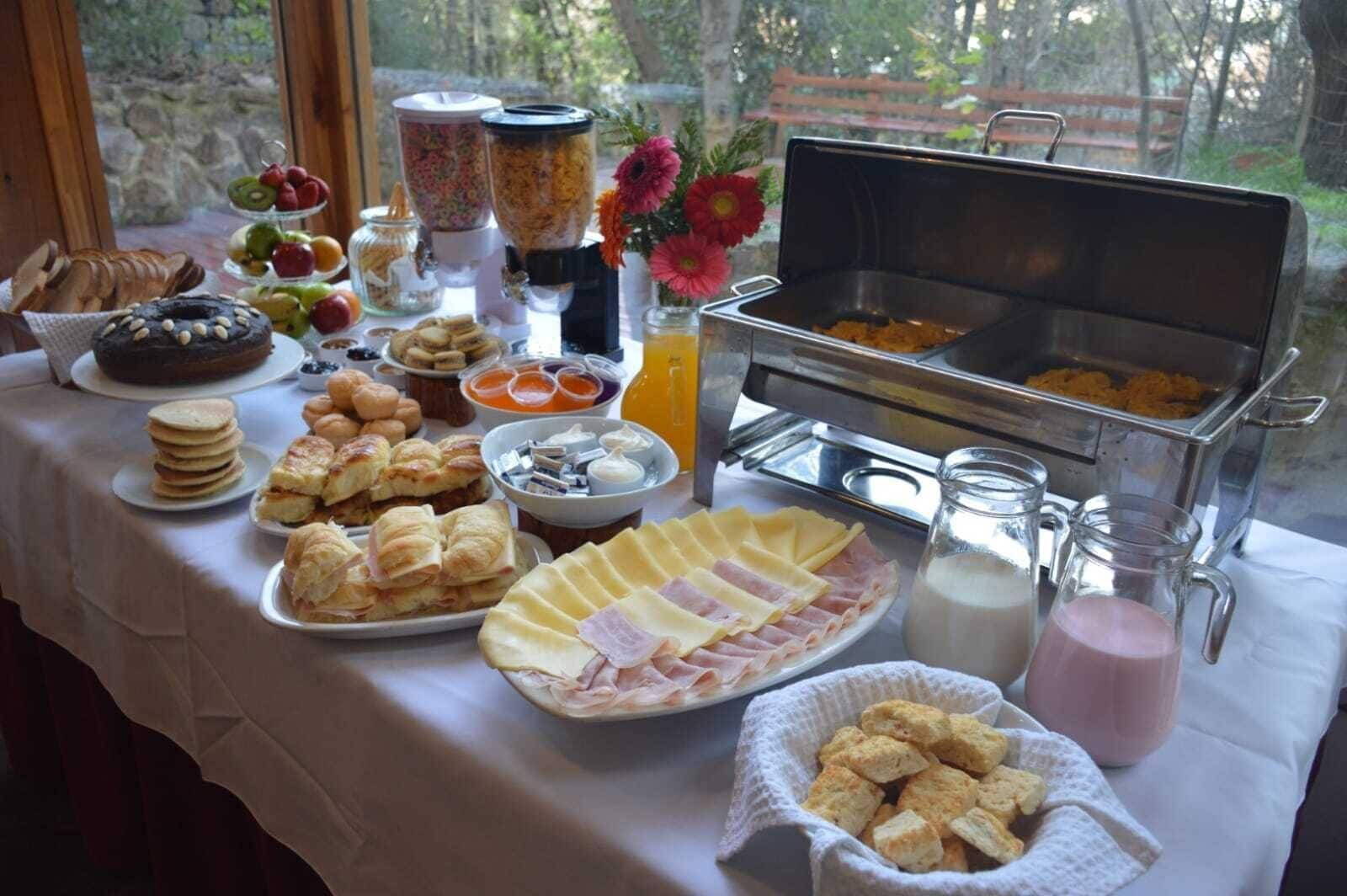 Een buffet met diverse gerechten, waaronder gebak, fruit en een buffetstation met warme maaltijden.