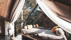 A bedroom with a bed, curtains, and a view of trees.
