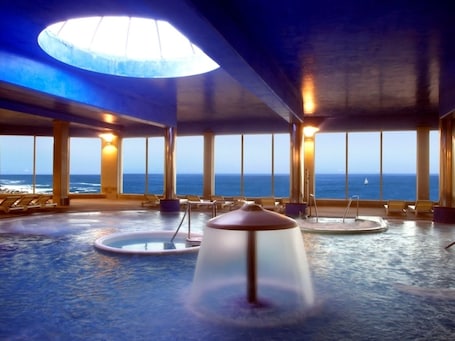 Una piscina techada, sillones reclinables de piscina