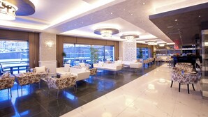 Eine geräumige Lobby mit moderner Einrichtung, großen Fenstern und einer zentralen Zierensäule.
