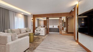 Ein modernes Hotelzimmer mit Wohnbereich, ausgestattet mit einer Sofagarnitur, einem Couchtisch und einem Fernseher.