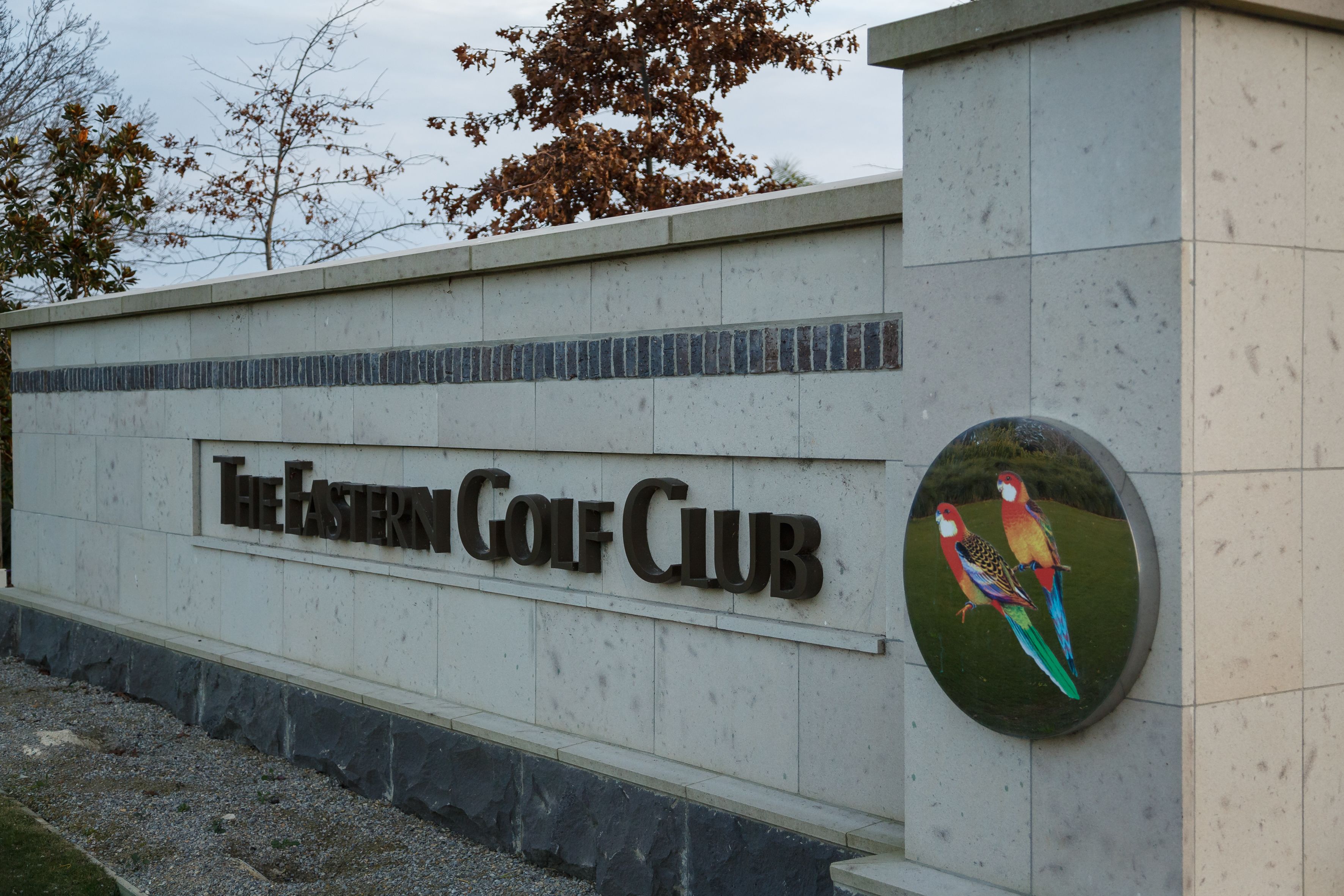 A sign for The Eastern Golf Club with a decorative bird mural.