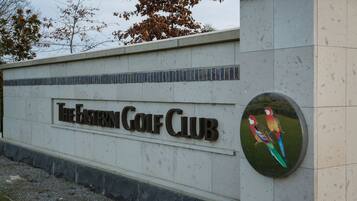 A sign for The Eastern Golf Club with a decorative bird mural.