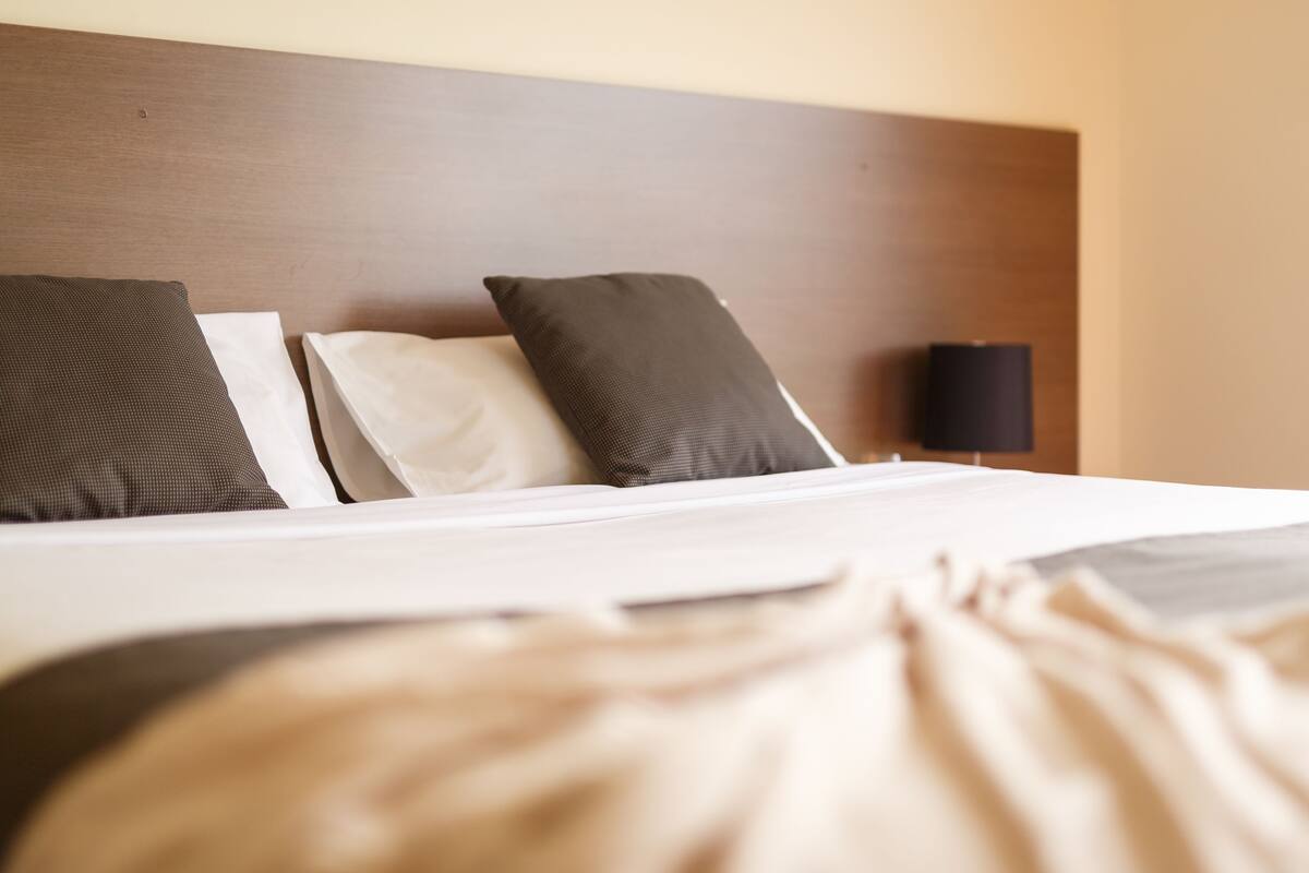 A neatly made bed with a wooden headboard, two pillows, and a bedside lamp.