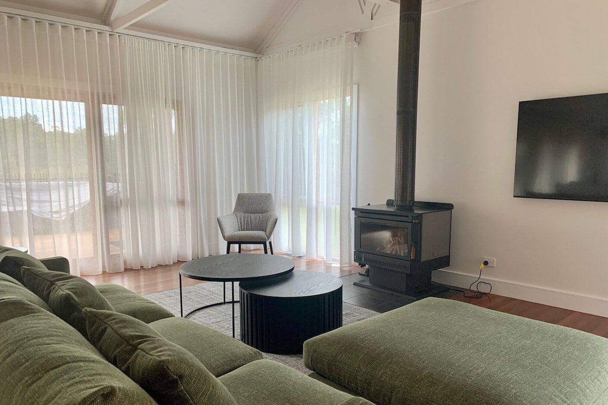 A living room with a sofa set, a round coffee table, a chair, and a wood-burning stove.