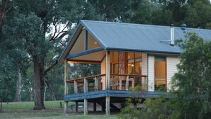 A wooden cabin with a balcony, surrounded by trees. - Yering Gorge Cottages (Yering)