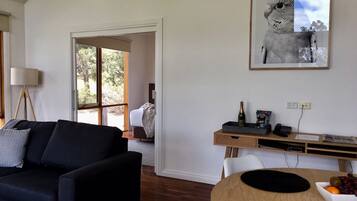 Ein modernes Wohnzimmer mit einem dunkelgrauen Sofa, einem Holzespeisetisch mit Obstschale und einem gerahmten Bild an der Wand.