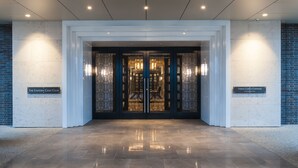 A modern building entrance with a glass door, two signs indicating 'The Eastern Golf Club' and 'Yering Gorge Cottages', and a polished stone floor. - Yering Gorge Cottages (Yering)