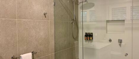 A modern bathroom with a glass-enclosed shower, a white sink, and a towel rack.