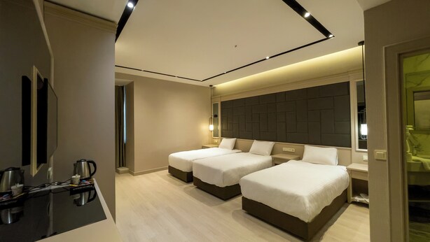 A modern hotel room with two beds, a flat-screen TV, a coffee machine, and a bathroom visible through an open door. - Martinenz Hotel (Istanbul)