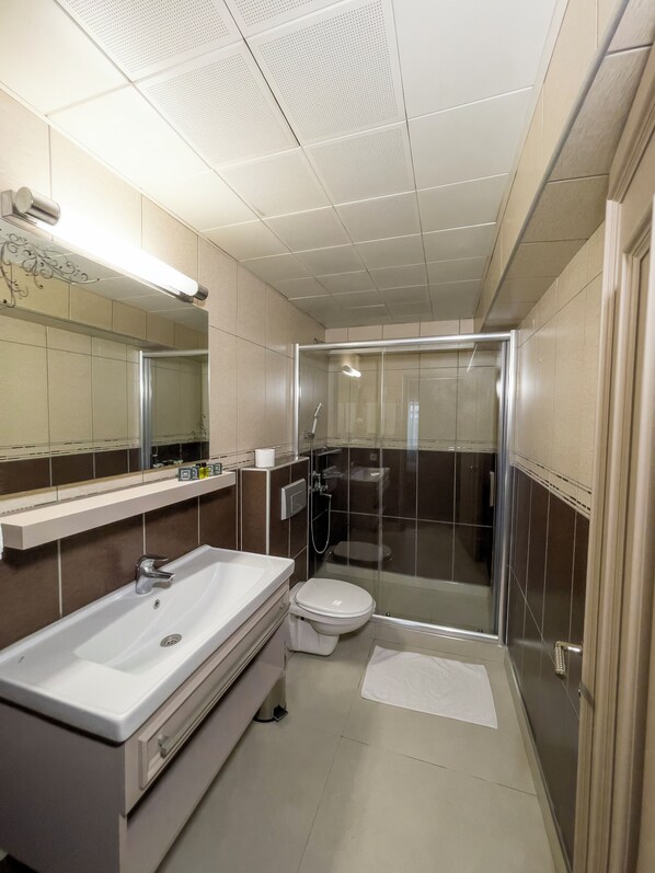 A modern bathroom with a large sink, toilet, and glass-enclosed shower. - Martinenz Hotel (Istanbul)