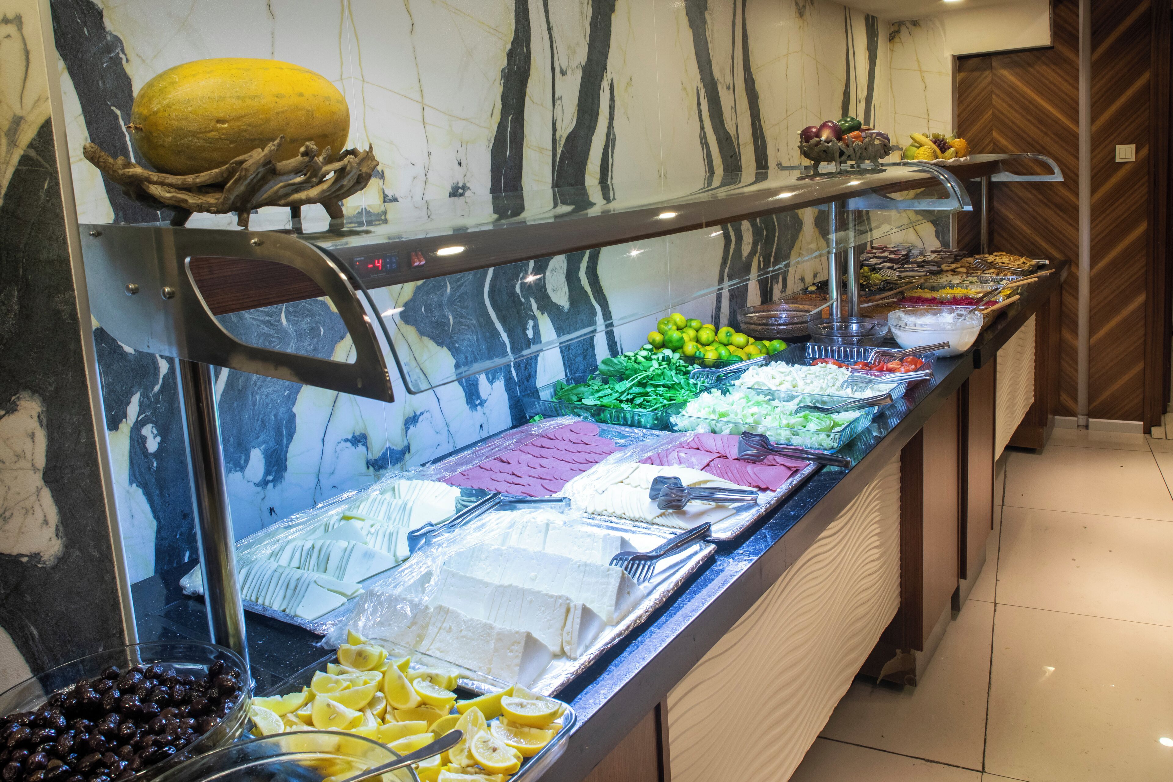 Un bufé con diversos alimentos, incluyendo frutas, verduras y quesos.
