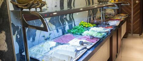 Un bufé con diversos alimentos, incluyendo frutas, verduras y quesos.