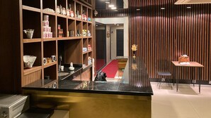 A hotel lobby with a reception desk, wooden shelving with various items, a red carpet, and a modern wall design. - Martinenz Hotel (Istanbul)